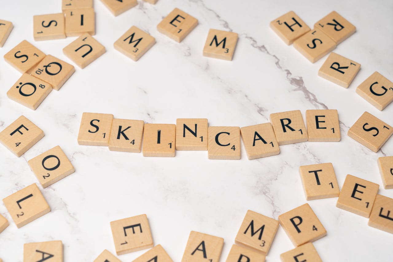 Wooden letter tiles spelling 'skincare' on a marble surface, symbolizing beauty.