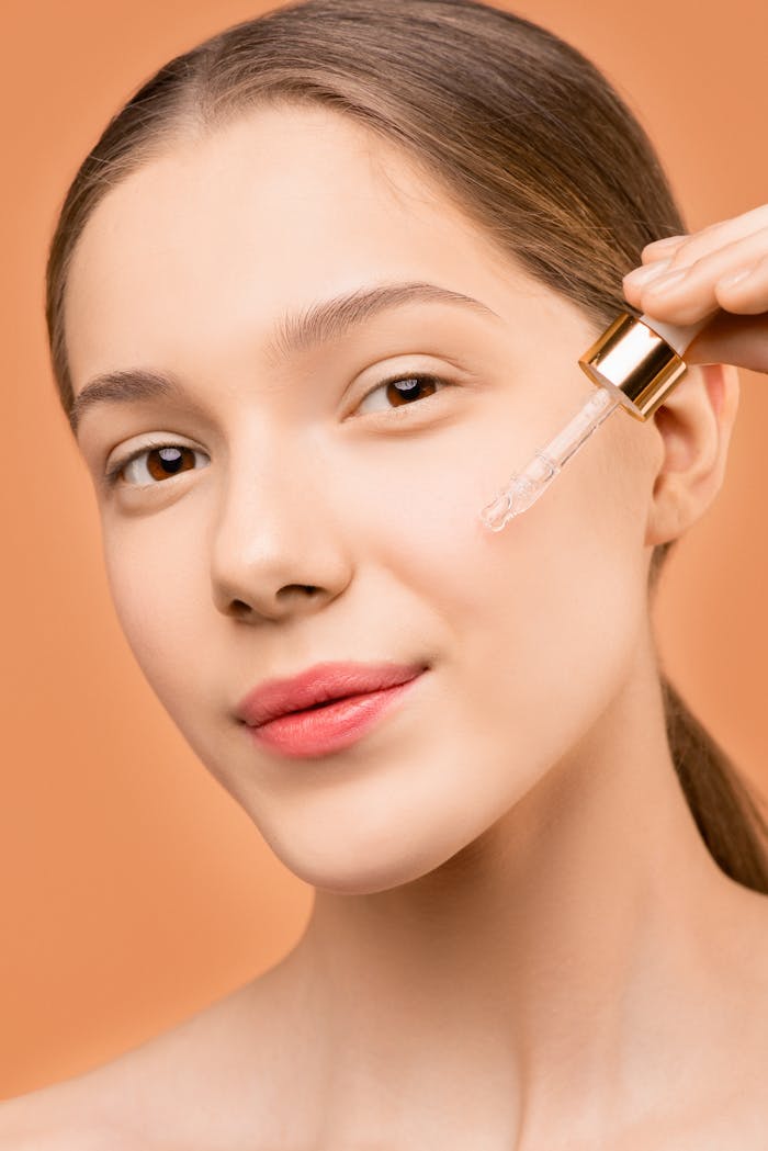 Mastering the First Impression: Your intriguing post title goes here Close-up of a young woman using a dropper to apply facial serum for skincare treatment.